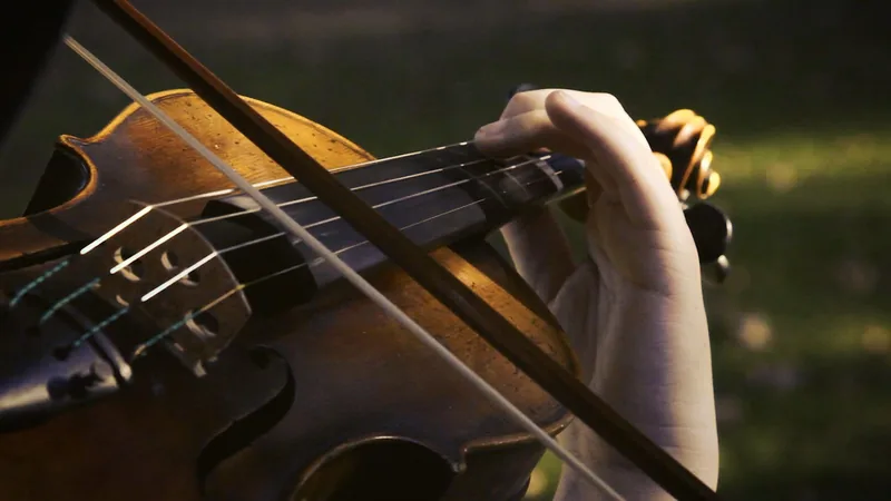 Close view of a student's hands finding a note on the viola in warm afternoon light.