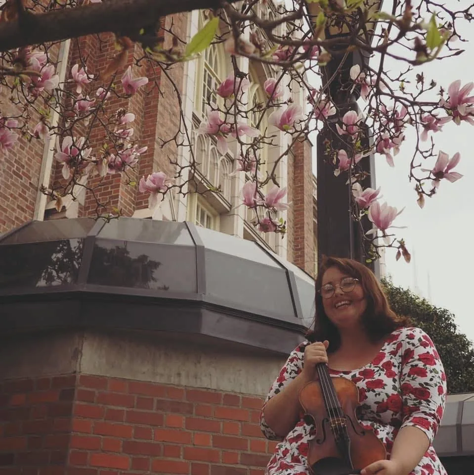 Emily Gasper with her viola beneath magnolia blossoms.